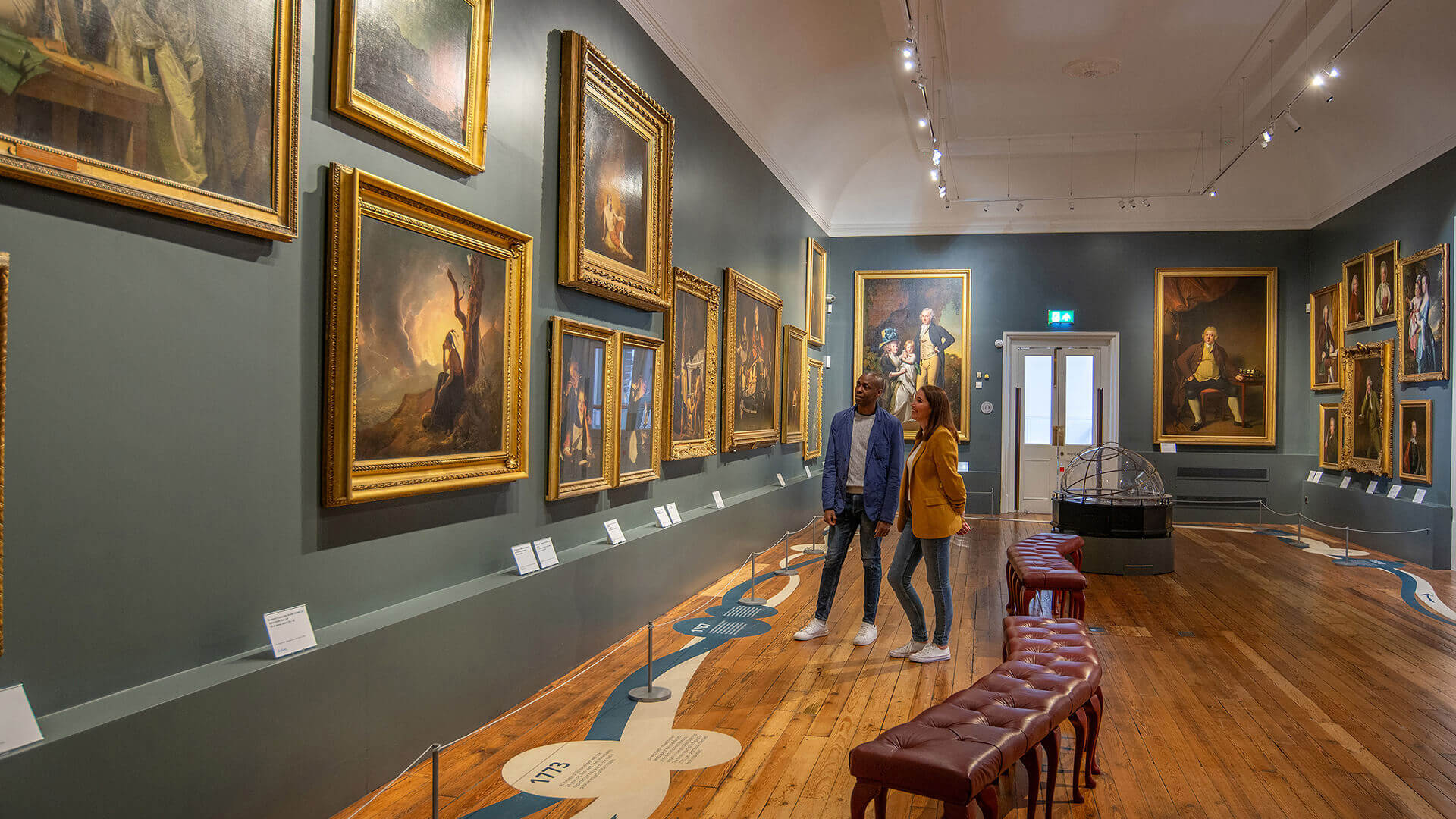 Two people admiring paintings in a gallery in Derby